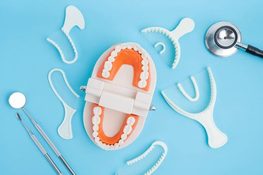 dentadura de muestra y útiles de dentista sobre fondo azul